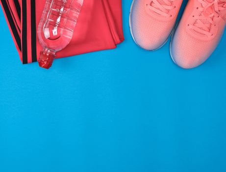 sport textile shoes and other items for fitness on a blue background, top view, copy space