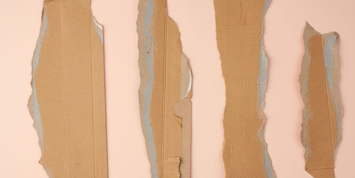 pieces of cardboard corrugated paper torn edges on a beige background, abstract backdrop. Ripped paper texture.