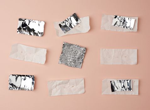 various crumpled foil used candy wrappers on a beige background, top view