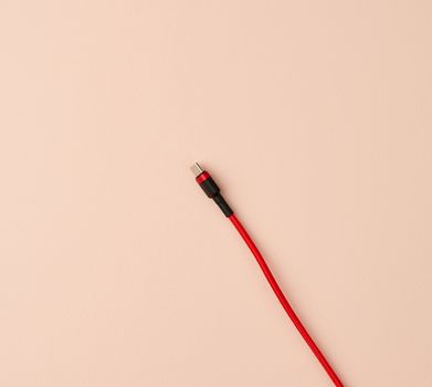 micro cable for charging mobile devices in a red textile braid on a beige background
