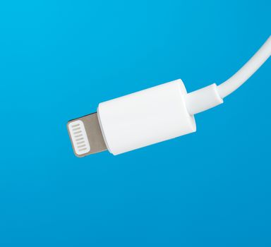 White lightning cable on a blue background, close up