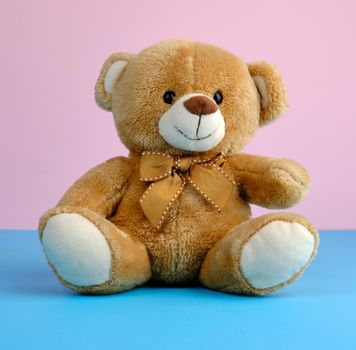 cute little brown teddy bear, toy is sitting on a blue background, close up