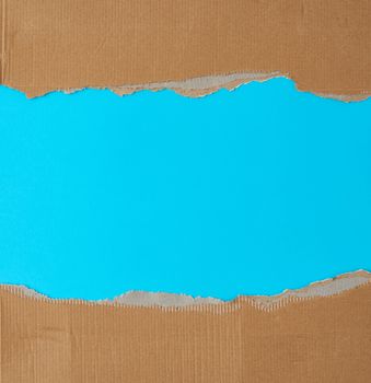 torn edges of corrugated cardboard paper with light blue background, abstract backdrop template, copy space