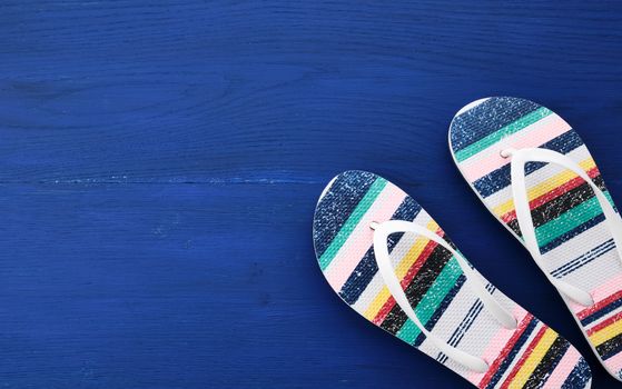 Flip flop in flat style on blue wooden background. Female fashion set. Top view