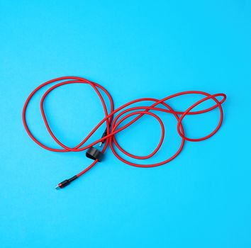twisted cable for charging mobile devices in a red textile wrapper on a blue background