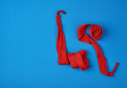 pair of textile red bandages for winding hands to athletes before sports training on a blue background, top view