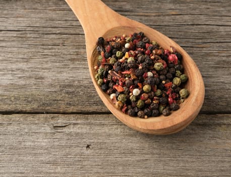 mix of dry balls of various peppers in a wooden spoon, top view