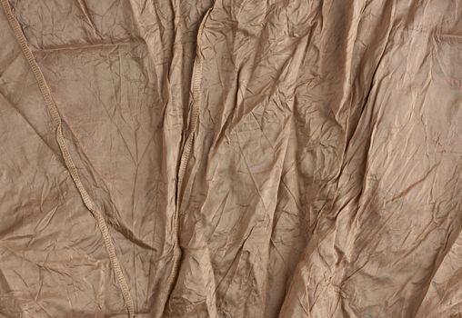 texture of crumpled brown synthetic fabric with seams for sewing clothes, full frame