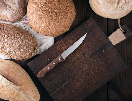 baked various breads on a beige kitchen towel, wooden background, top view, copy space