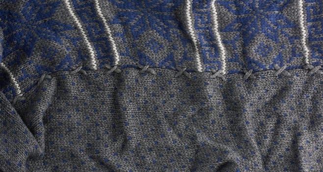gray knitted fabric with a blue pattern, full frame, detail of a woolen scarf