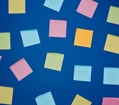 multicolored blank paper stickers of different colors on a dark blue background, copy space