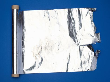 roll of gray foil for baking and packaging food on a dark blue background, torn edge