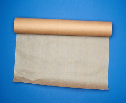 roll of brown parchment paper on a blue background, copy space, top view