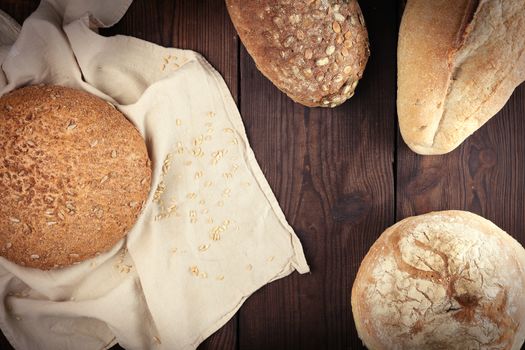 baked various breads on a beige kitchen towel, wooden background, top view, copy space