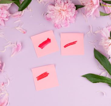 liquid lipstick and a smear of red lipstick on a pink paper sticker, purple background