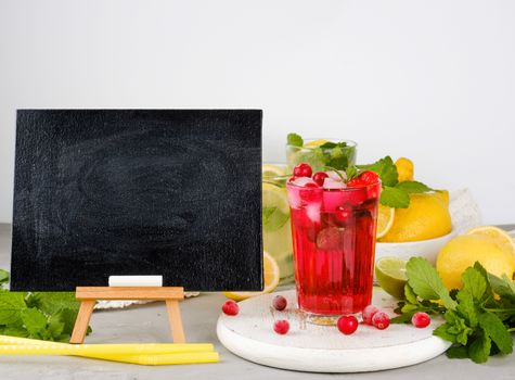 empty black chalk board for writing a summer drink recipe and a glass with berry lemonade, close up