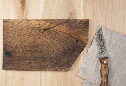 old empty wooden rectangular cutting board and knife, top view, beige wooden background 