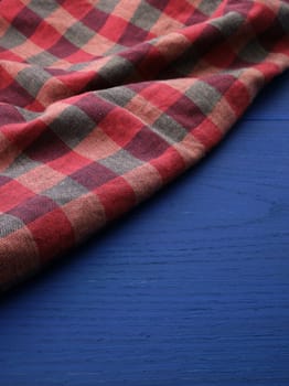 red checkered fabric on a blue wooden background, abstract background, place for an inscription