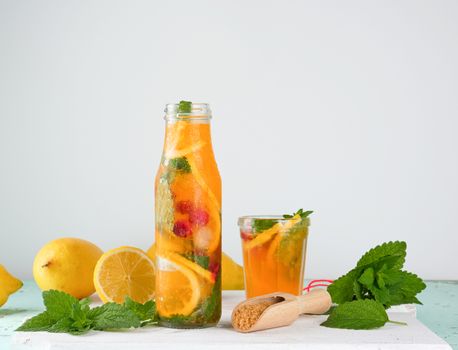 summer refreshing drink lemonade with lemons, cranberry, mint leaves, lime in a glass bottle, next to the ingredients for making a cocktail