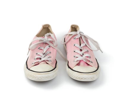 pair of light pink worn textile sneakers with laces isolated on a white background, front view