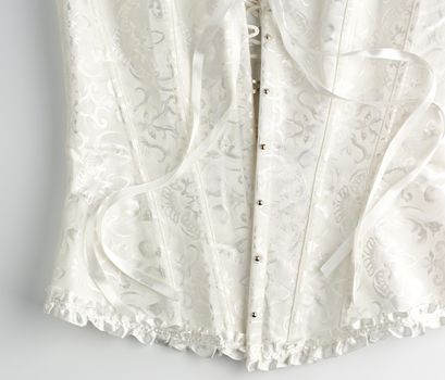 fragment of a white satin corset with lacing, front closure with iron buttons, white background