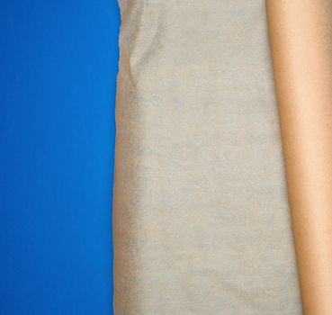 roll of brown parchment paper on a blue background, copy space, top view