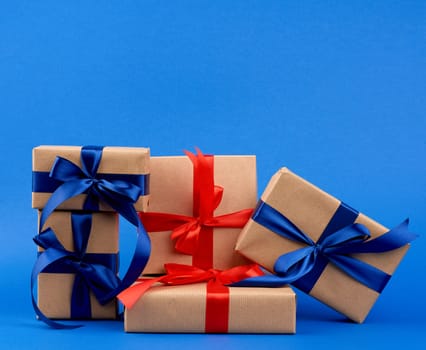 rectangle box wrapped in brown kraft paper and tied with a silk blue and red ribbon, gift on a dark blue background, holiday backdrop 