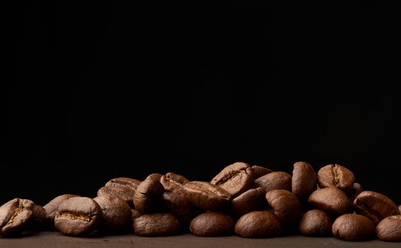 roasted coffee beans arabica on a wooden table, black background, place for an inscription