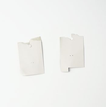 torn piece of white cardboard paper on a white background, close up