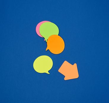 multicolored empty paper stickers in the form of clouds on a blue background, copy space