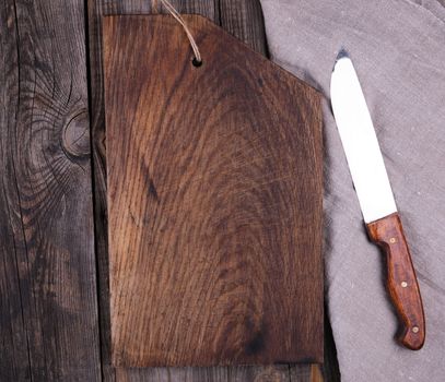very old empty wooden rectangular cutting board and knife, top view, gray wooden background 