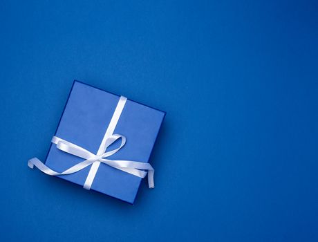 blue square box with a gift with a bow on a blue classic background, top view, empty place for an inscription