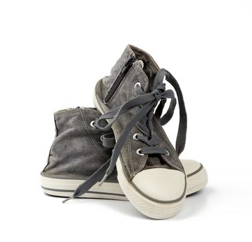 pair of black well-worn, shabby sneakers with white laces isolated on a white background