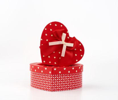 red heart-shaped cardboard box with bow on white background, holiday gift wrapping