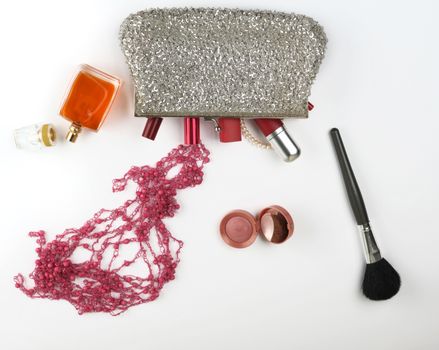 open silver cosmetic bag and women's cosmetics and perfumes, red lipstick, perfume on a white background