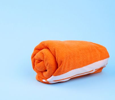 twisted orange terry towel on a blue background, close up