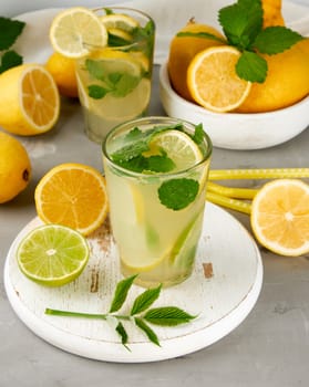 summer refreshing drink lemonade with lemons, mint leaves, lime in a glass, next to the ingredients for making a cocktail