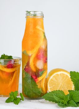 summer refreshing drink lemonade with lemons, cranberry, mint leaves, lime in a glass bottle, next to the ingredients for making a cocktail