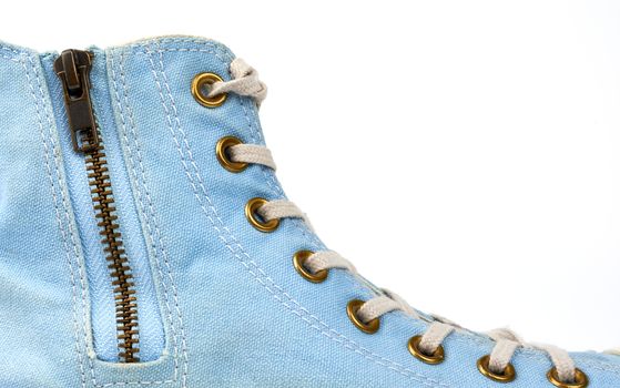 fragment of a blue sneaker with white textile laces and an iron zipper clasp on a white background, close up