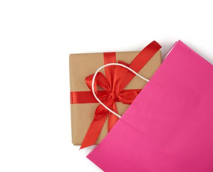 pink paper bag with a gift box on a white background, concept of shopping and giving a gift, flat lay