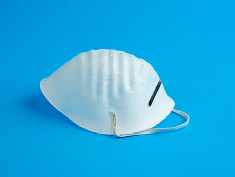 masks made of non-woven material with white rubber bands on a blue background, protective accessory for the respiratory tract from the virus, top view