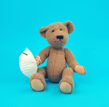brown teddy bear are sitting in medical masks on a blue background, concept of protection from respiratory disease, virus and individual respiratory protection