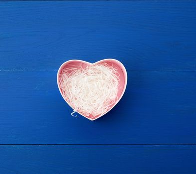 open empty heart-shaped box on a blue wooden background, top view