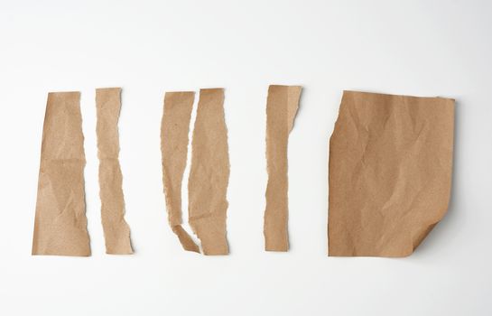 torn brown pieces of parchment paper on a white background, flat lay