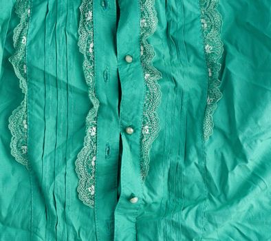 fragment of a female green shirt with lace and buttons, full frame