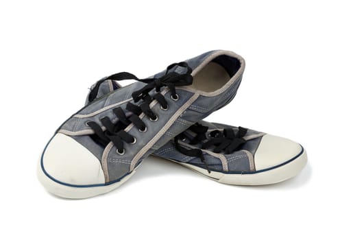 pair of blue worn textile sneakers with black laces isolated on a white background, front view