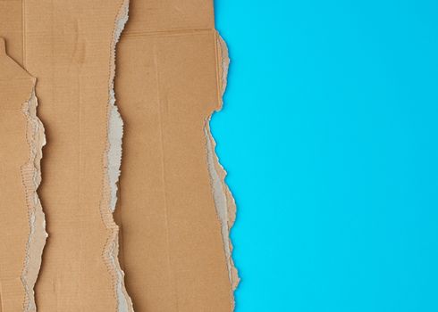 torn edges of corrugated cardboard paper on a light blue background, abstract template, copy space