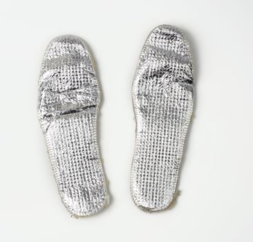 pair of shoe insoles with insulation and foil on a white background, top view