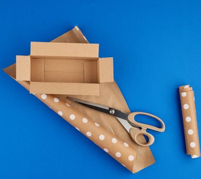 empty cardboard brown box, roll of wrapping paper and scissors, items for packing a gift