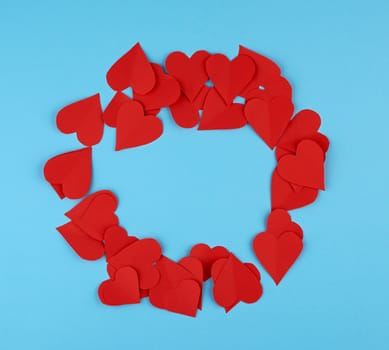 hearts cut out of red paper on a blue background, festive backdrop for Valentine's Day, copy space